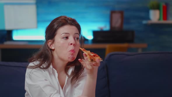 Young Person Eating Slice of Pizza While Watching Television