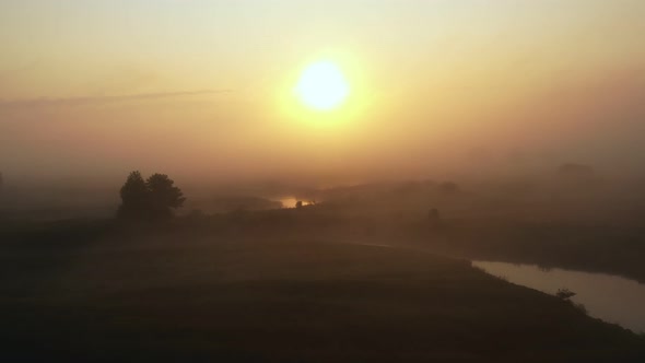 Incredible Atmospheric Aerial Flyover Above Foggy Valley and Winding River Covered with Thick Mist