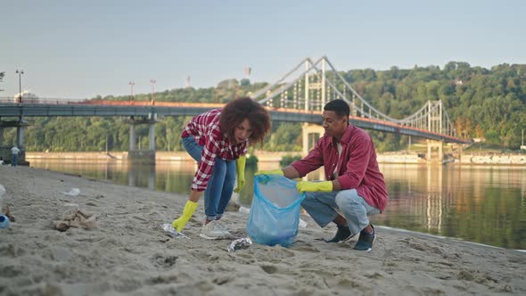 Couple of Ecologists Gather Trash in Bag Together on Beach