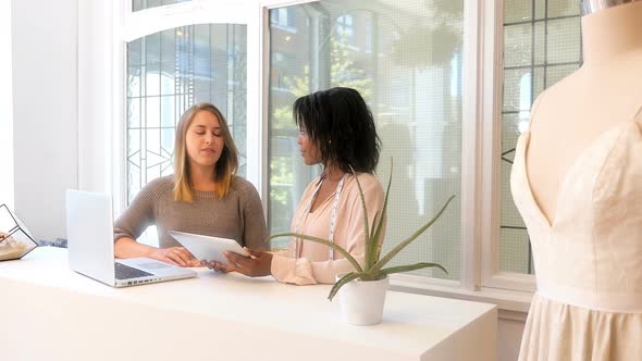 Female fashion designers having discussion on digital tablet