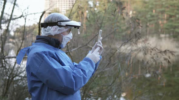 A biologist takes water samples from the river for laboratory research.