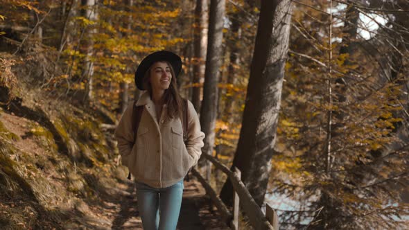 Woman Tourist Walks on Trail in Fall Forest on Sunny Autumn Day