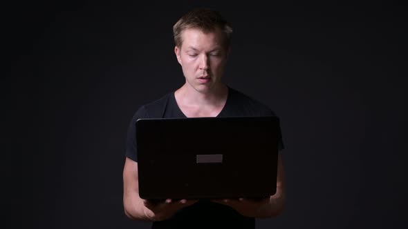 Young Handsome Man with Laptop Against Black Background