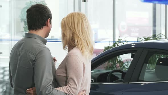 Rearview Shot of a Mature Couple Examining a New Car at the Dealership 1080p