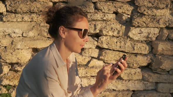 Woman with smartphone on a stone wall background.