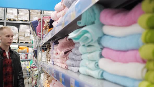 Young Couple Guy and Girl are Choosing Towels at Supermarket