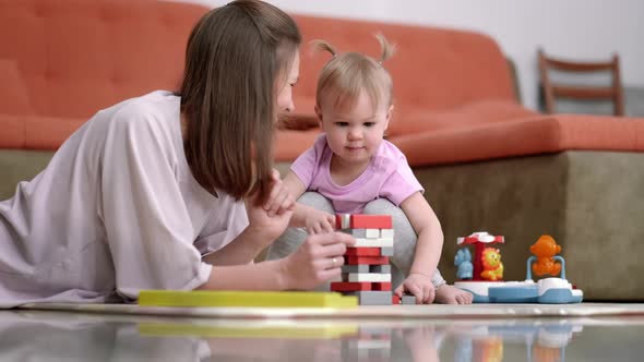 Little Baby Girl and Mommy Playing Color Wooden Toys at Home Sitting on Floor Mother and Daughter