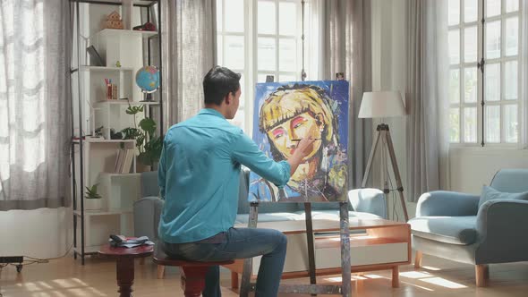 Asian Artist Man Holding Paintbrush Mixed Colour And Thinking Before Painting A Girl's On The Canvas