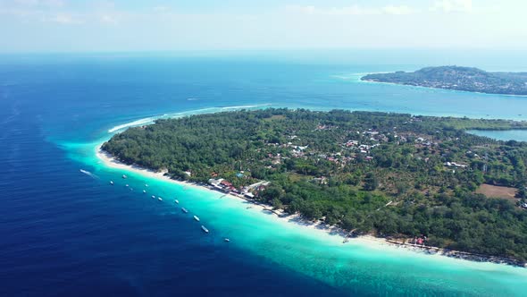 Daytime above clean view of a white sandy paradise beach and blue ocean background in vibrant 4K