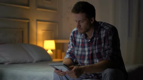 Unhappy Lonely Young Male Sitting on Bed Looking at Photo, Breakup, Missing Wife