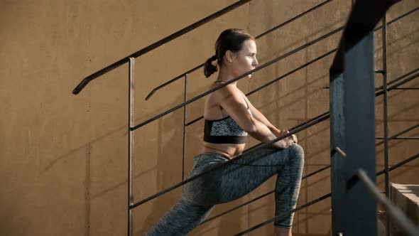 Fitness woman stretching legs on stairs before workout