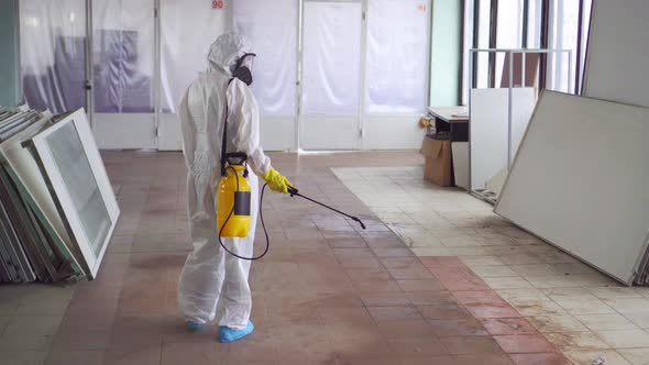 Exterminator in Special Clothes and in a Protective Mask Sprays Pesticiderear View