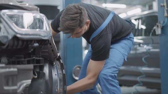 Young Repairman Unscrewing Wheel Bolts in Auto Repair Shop