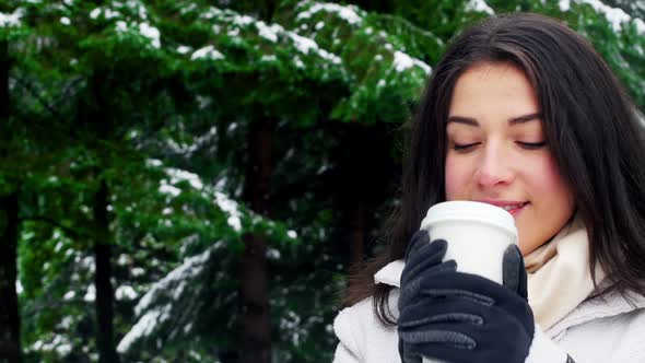 Woman in warm clothing having coffee during snowfall
