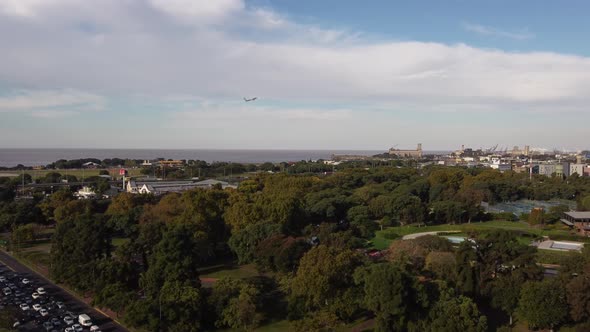 Drone flying over Palermo park with airplane taking off in background. Aerial forward