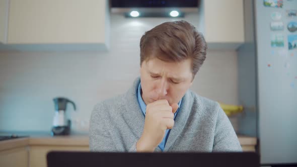 Sick Man Coughs at Home While Sitting at Laptop