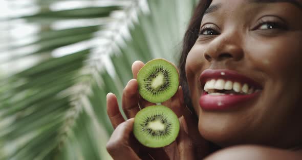 Kiwi in the Hands of a Beautiful Girl Holding a Circle of Faces Close Up