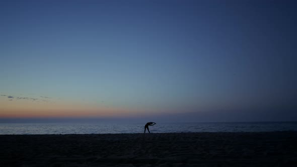 Silhouette Athlete Girl Exercising on Seacoast at Dusk