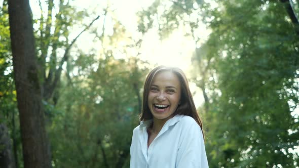 Shot Near of a Pretty and Positive Girl Who Is Spinning Among the Trees in a City Park. Beautiful