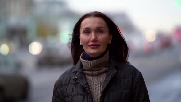 Portrait of a Middle-aged Dark-haired Woman in a Black Jacket Walking Against the Background of a