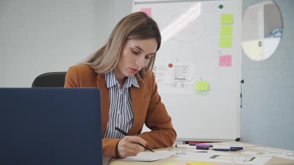 Beautiful American Businesswoman Writing in Document, Working at Desk with Laptop in Office.