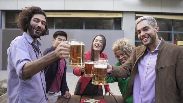 Happy Multiracial Friends Toasting Beer in a Celebration Looking to Camera