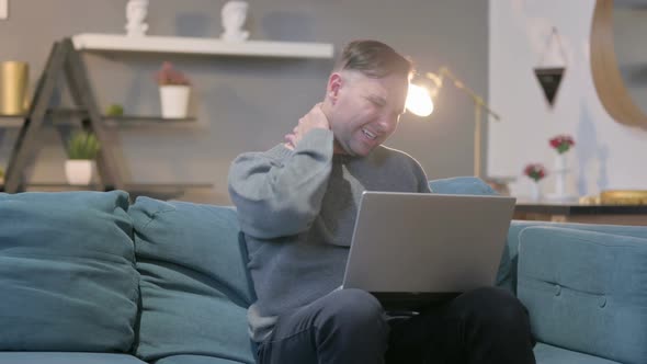 Casual Manwith Laptop Having Neck Pain on Sofa