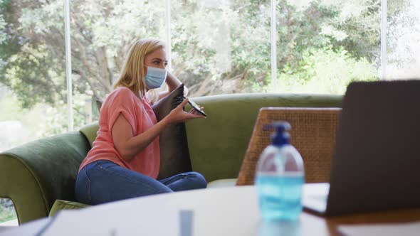 Woman wearing face mask talking on smartphone at home