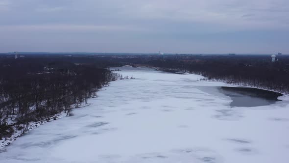 An aerial view from a drone, over a long lake during sunrise on a cloudy morning. The camera dolly i