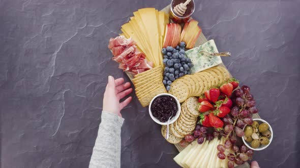 Flat lay. Arranging gourmet cheese, crakers, and fruits on a board for a large cheese board.