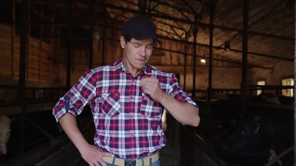 Young Attractive Dairy Farm Worker Scratch His Nose and Smiling at Camera