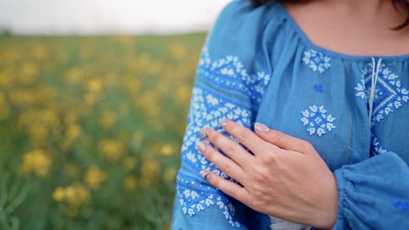 Woman Demonstrates Beautiful Details of Blue Embroidery Ornament on Vyshyvanka Shirt