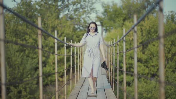 Woman in a Beautiful Dress, Walks on a Bridge in Woods