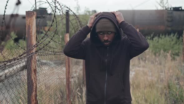 Black Refugee Man by Barbed Wire Fence