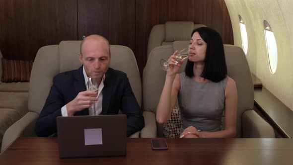 Young Couple Man Woman clink Glasses and Drink Champagne, Fly Business jet Private Jet