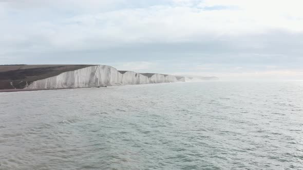 dolly forward rising drone shot towards seven sisters white chalk cliffs South England coast