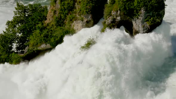 Tilt up close up shot of giant waterfall dashing against rock of rhine fall during sunny day