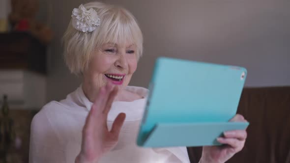 Portrait of Charming Elegant Senior Woman in Wedding Dress Waving Talking in Video Chat on Tablet in