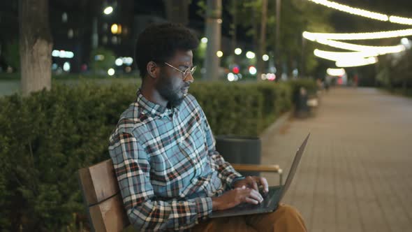 Afro Man Using Laptop in Park in Evening