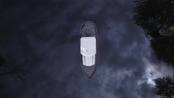 birdseye view of an old boat in the middle of a swampy, dark river