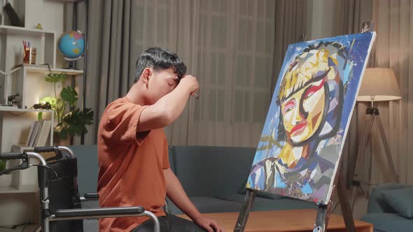 Asian Artist Boy In Wheelchair Holding Paintbrush Turn To Cross His Arms And Smile To camera