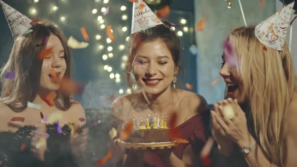 Portrait of Attractive Asian Girl Blowing Out Fire Candles on Birthday Cake Under Falling Glowing