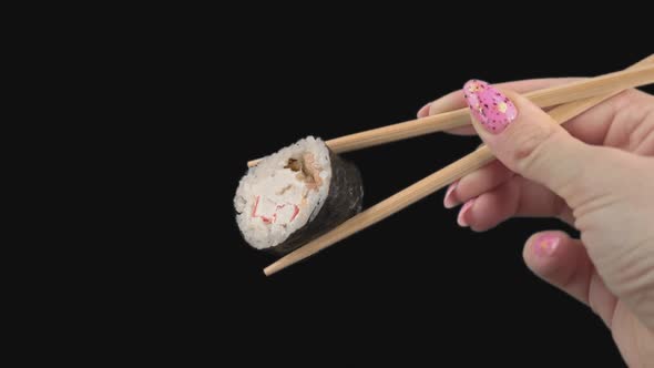 Female Hands Hold Japanese Chopsticks with Sushi Rolls on Transparent Background
