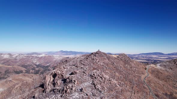 Drone aerial view orbiting a rocky and snowy mountain peak above everything