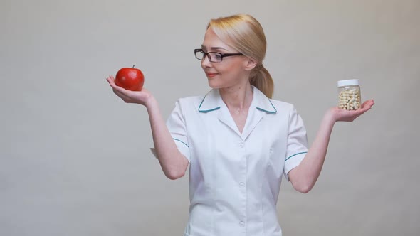 Nutritionist Doctor Healthy Lifestyle Concept - Holding Organic Red Apple and Jar of Vitamin Pills