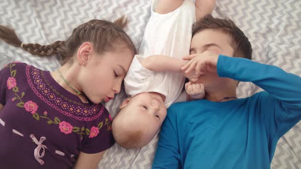 Three Children Together. Portrait of Happy Siblings Kissing Baby Brother