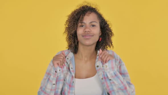 Young African Woman Dancing in Joy on Yellow Background