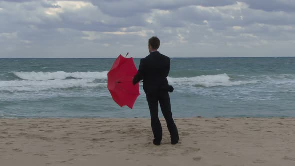 Male opening an umbrella on a beach