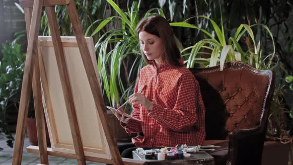 Artist in a Workshop  Young Beautiful Woman Drawing a Painting with Colors