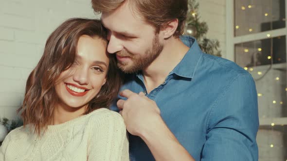 Smiling beautiful woman and her handsome boyfriend posing in New Year interior 